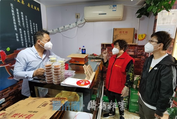 北坦街道北关社区第一网格网格员唐秀珍（红衣），提醒五小场所人员进行核酸检测（崔健 摄）