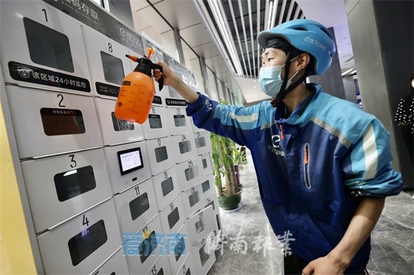 4月26日，在山东数字产业大厦，保洁人员和外卖小哥对写字楼的快递柜、外卖柜进行消杀。（赵晓明 摄）
